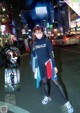 A woman standing in the middle of a city street at night.